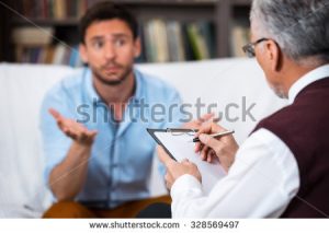 stock-photo-sad-young-man-talking-with-psychologist-psychologist-taking-notes-there-are-many-books-in-328569497